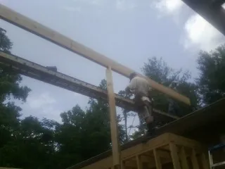 Carpenter setting a ridge beam over a new addition frame — Ice Dam Removal by Roofing Brothers in Hartline