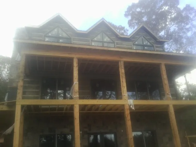 Dormers and porch framing on a large log home under construction — Roof Coating work by our crew in Hartline