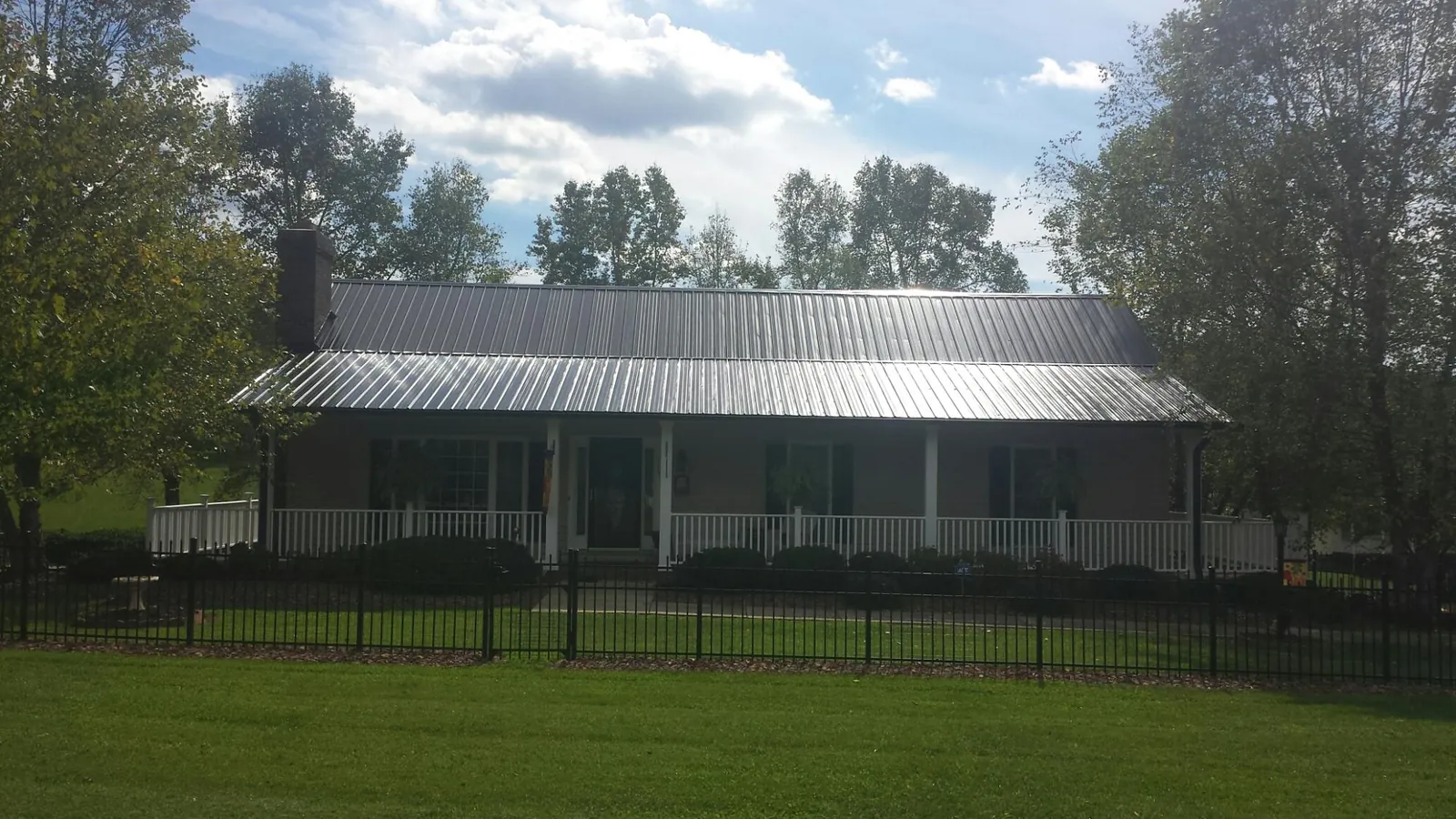 Gray metal roof on a brick ranch with a full width front porch — Gutter Guard Installation work by our crew in Hartline