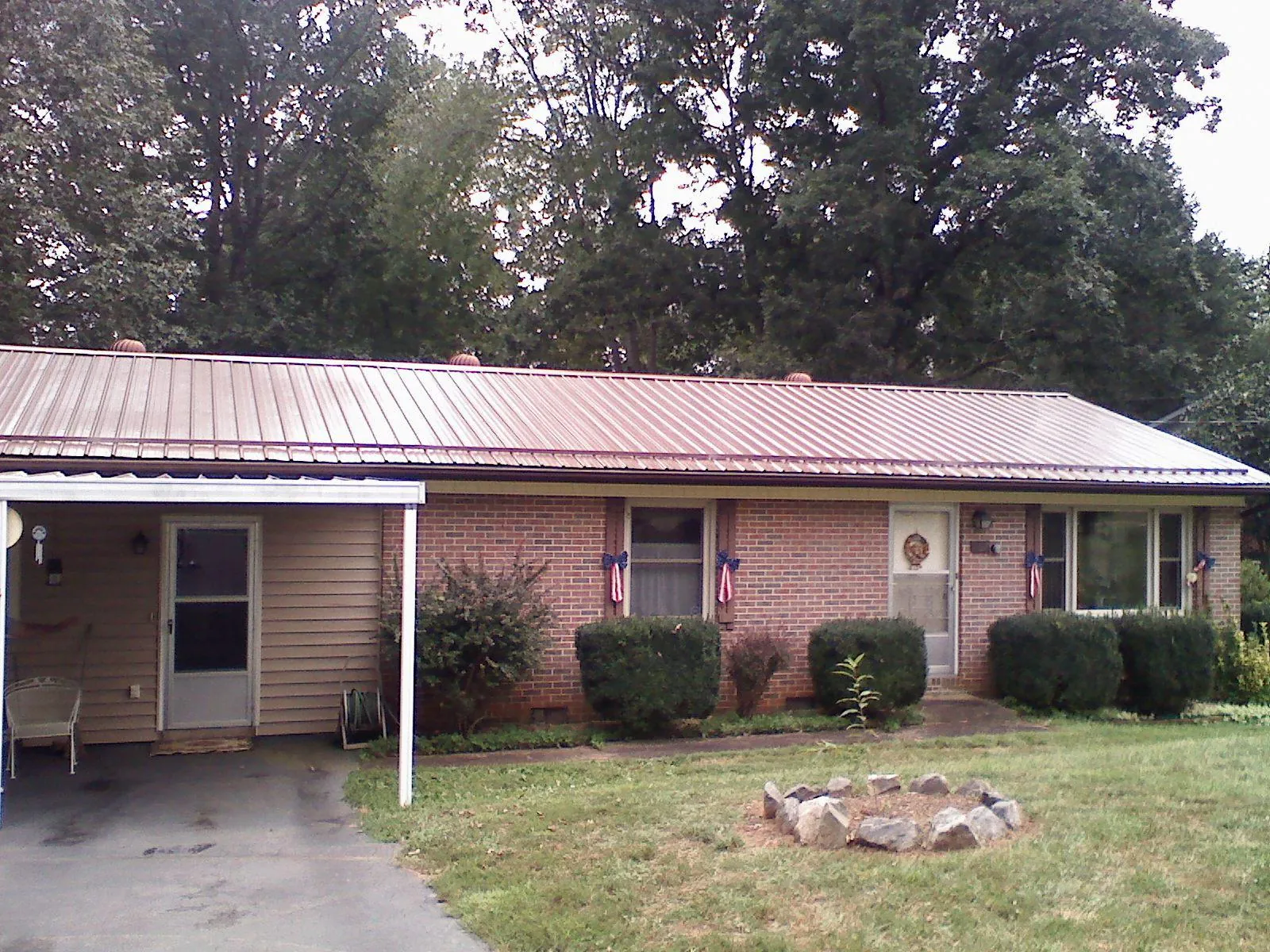 Bronze metal roof and carport on a brick ranch home — Roof Repair work by our crew in Hartline