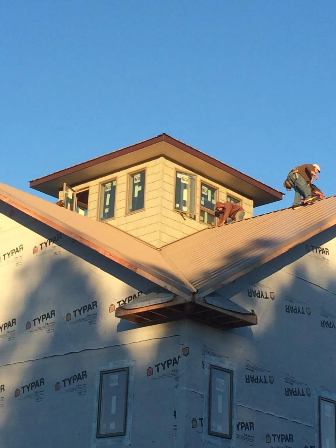 Roofers working around a rooftop cupola on a new metal roof at sunset — Roof Waterproofing in Hartline by Roofing Brothers